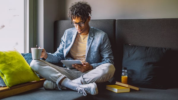 Man op een bank met koffie en iPad